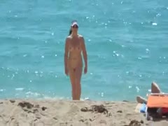 On a beach, naked amateur milf is captured on my covert webcam.